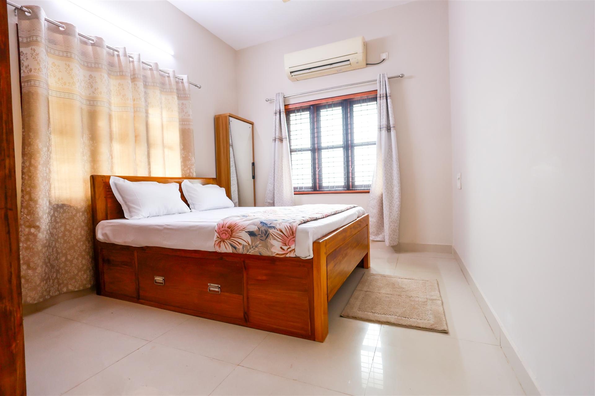 Bedroom 1 — AC room with teak wood bed and floral bedding